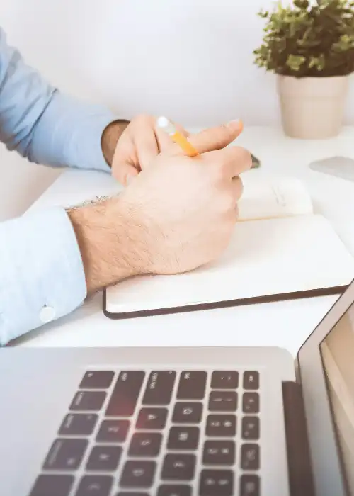 Homem com duas mãos encostando no teclado do notebook, com a tela ligada mostrando diversos gráficos.