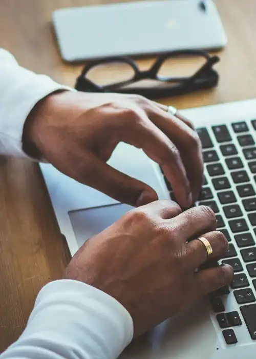 Homem com duas mãos encostando no teclado do notebook, com a tela ligada mostrando diversos gráficos.